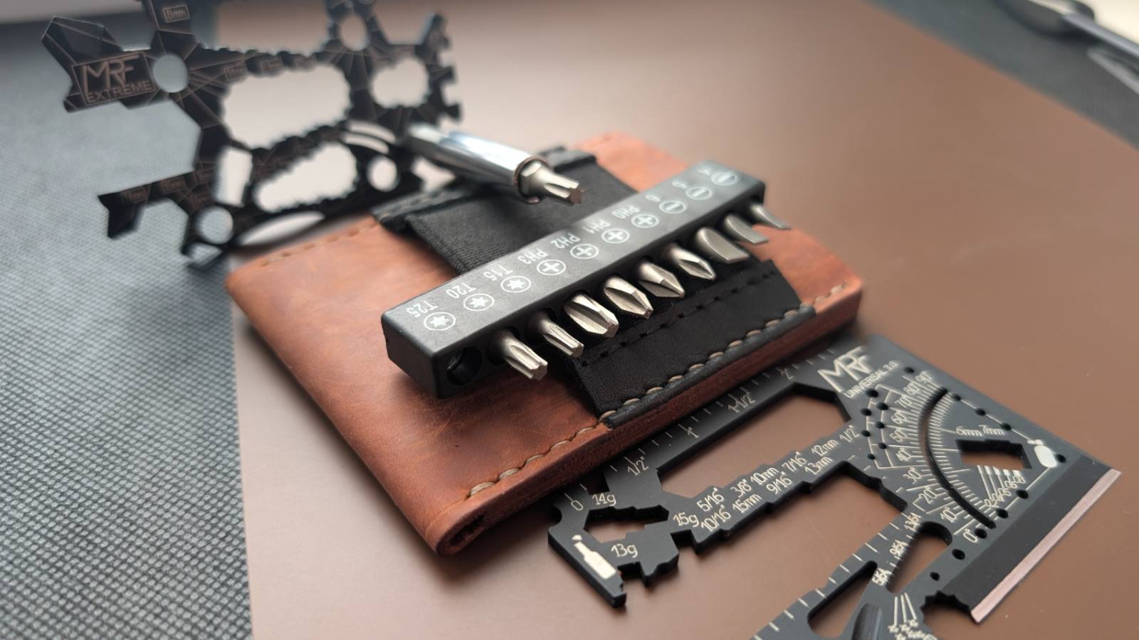 A bit bar with eight double-sided bits resting on the elastic loops of a brown leather MRF holder, cards beside it