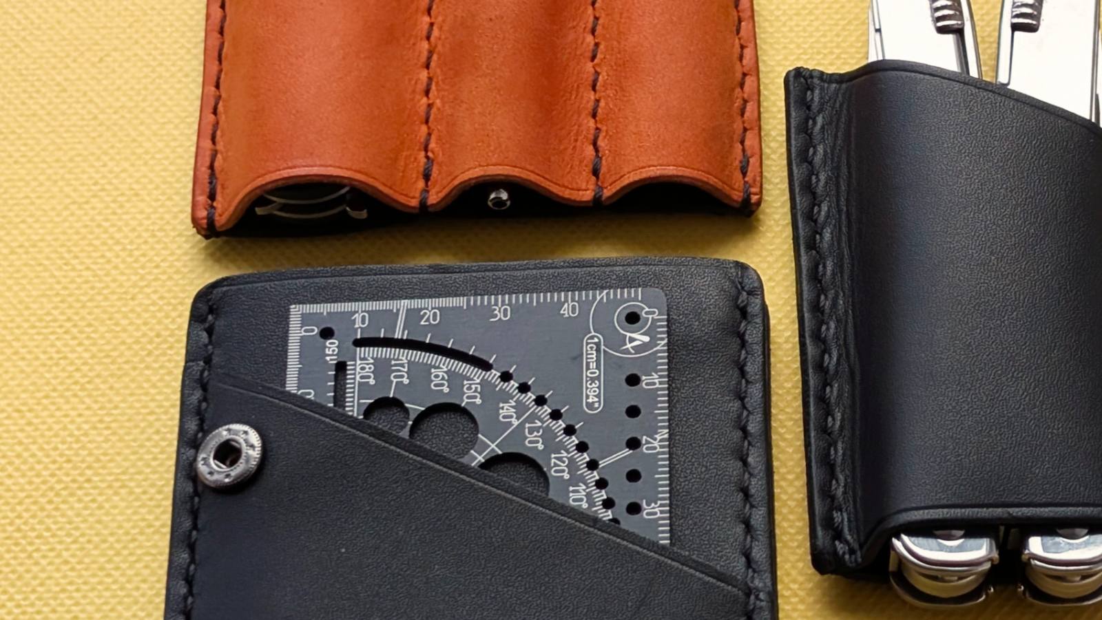 Orange and black MRF leather holders on a yellow background, one holding a red Extreme card