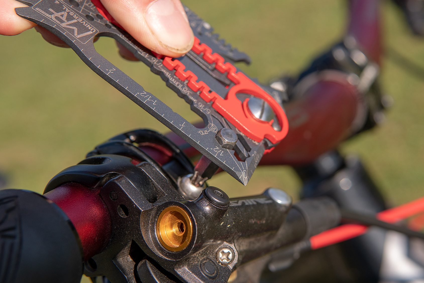 A 1/4-inch bit locked in the bit driver of a card multitool, driving a screw on a bicycle brake lever